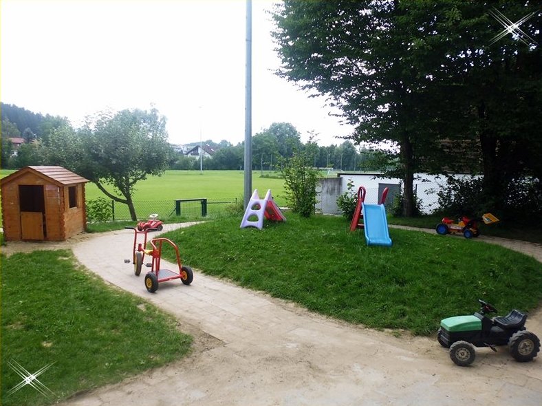 Außenbereich der Kindertagesstätte. Es ist sind Hütte und verschiedene Fahrzeuge auf dem Bild.