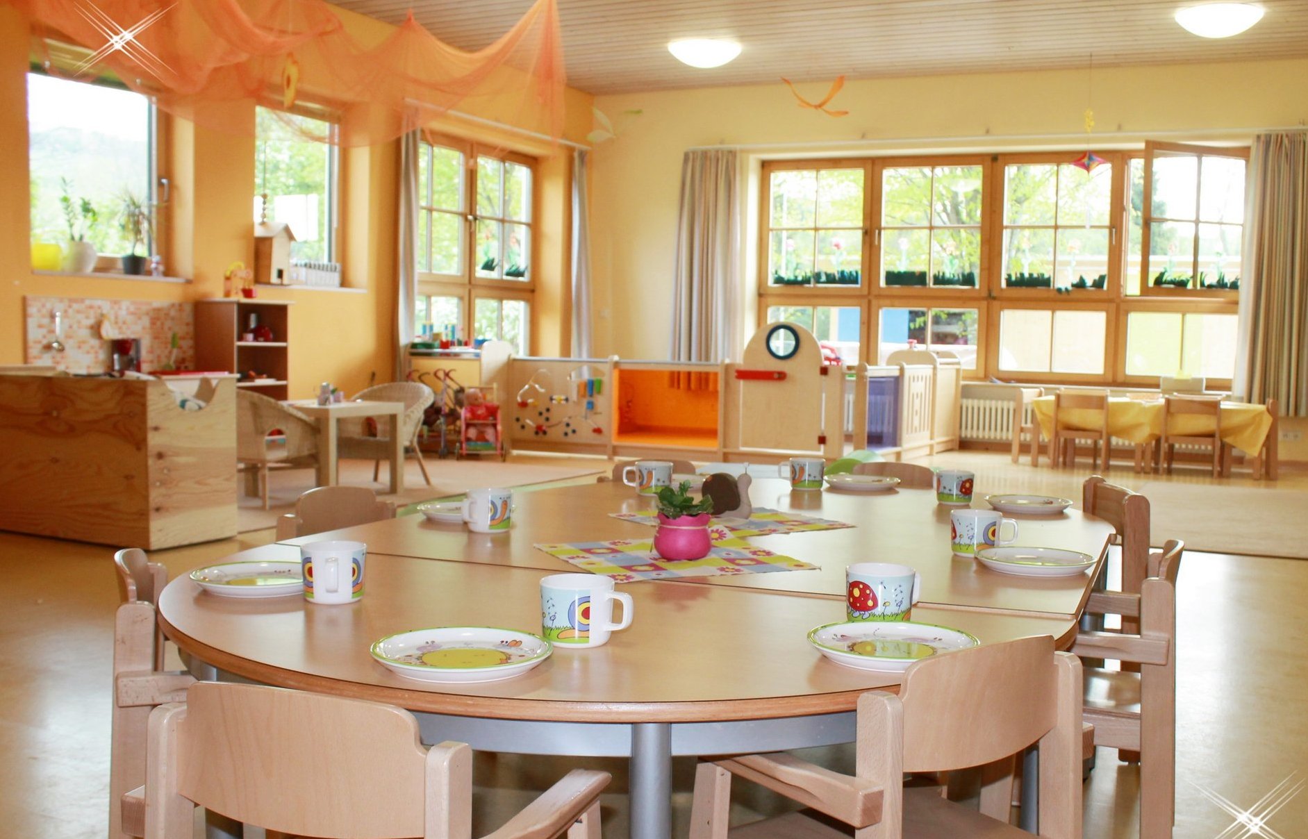 Innenraum des Kindergartens. Im Vordergrund steht ein gedeckter Tisch, der zum Essen einlädt.