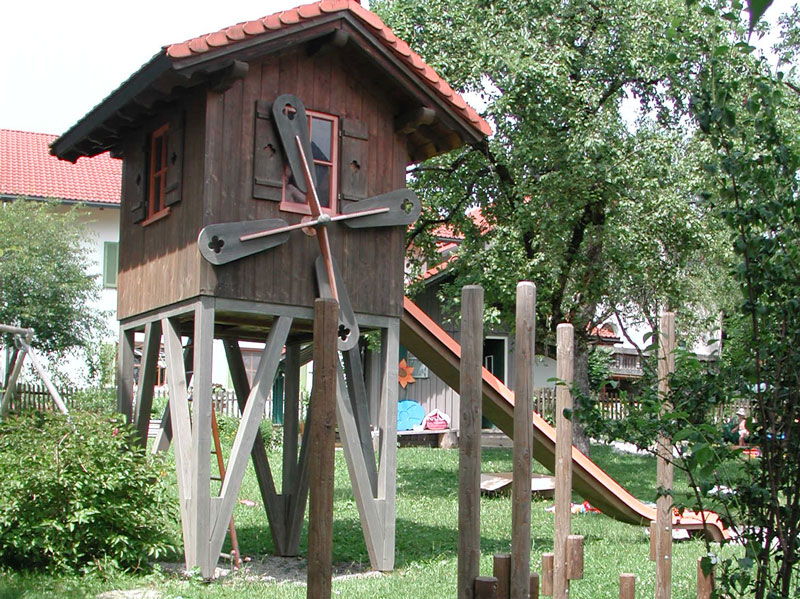 Baumhaus mit integrierter Rutsche und einem Windrad.